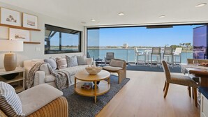 Un salon moderne doté d’une grande fenêtre, d’un canapé, d’une table basse et d’un coin repas avec des chaises.