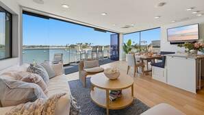 Un espace de vie moderne doté d’une grande fenêtre donnant sur un port de plaisance, d’un coin repas et d’une cuisine.