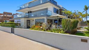 Une maison moderne à deux étages, dotée d’un balcon, d’un garage et d’un jardin bien entretenu.