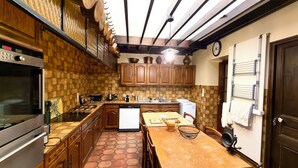 Una cucina con mobili in legno, un fornello a gas, una lavastoviglie e un pavimento piastrellato.