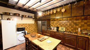 A kitchen with a refrigerator, microwave, stove, and hanging pots. - House near the château, steeped in history, on the edge of the forest (AVON)
