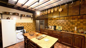 Eine Küche mit Kühlschrank, Mikrowelle, Herd und hängenden Töpfen.