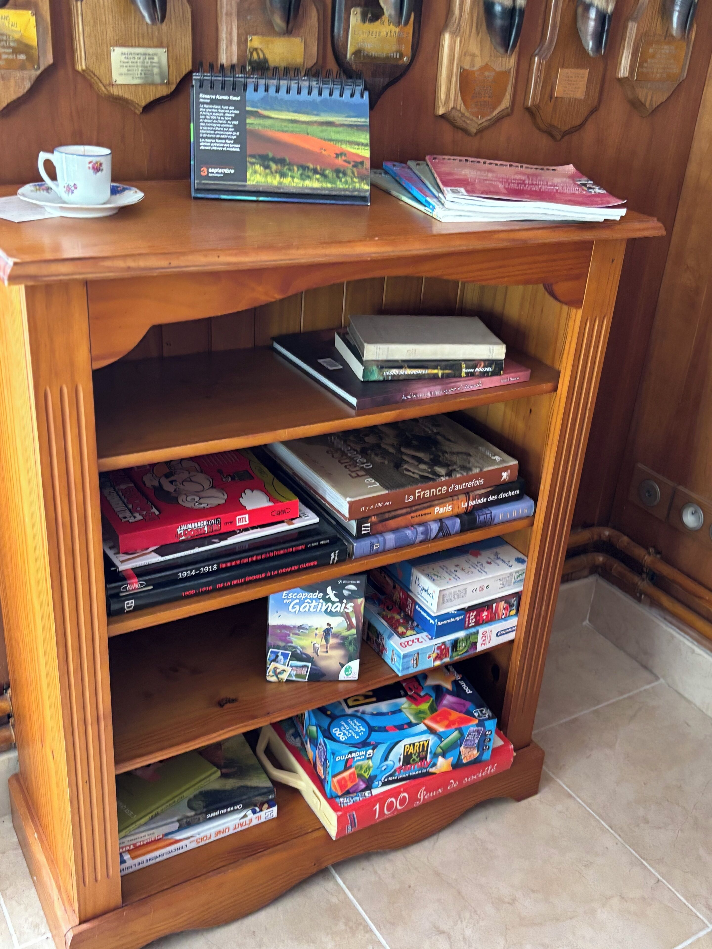 Une bibliothèque en bois contenant divers livres, un calendrier et une tasse de café.