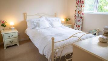 A bedroom with a bed, bedside tables, a lamp, and a window with curtains.