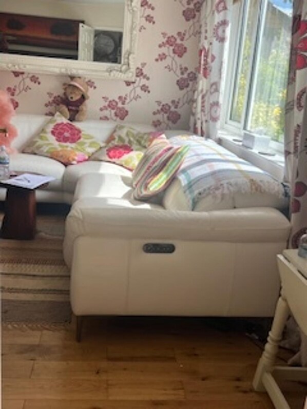 Ein Zimmer mit einer Couch, einem kleinen Tisch, einer Lampe und einem Fenster mit Vorhängen.