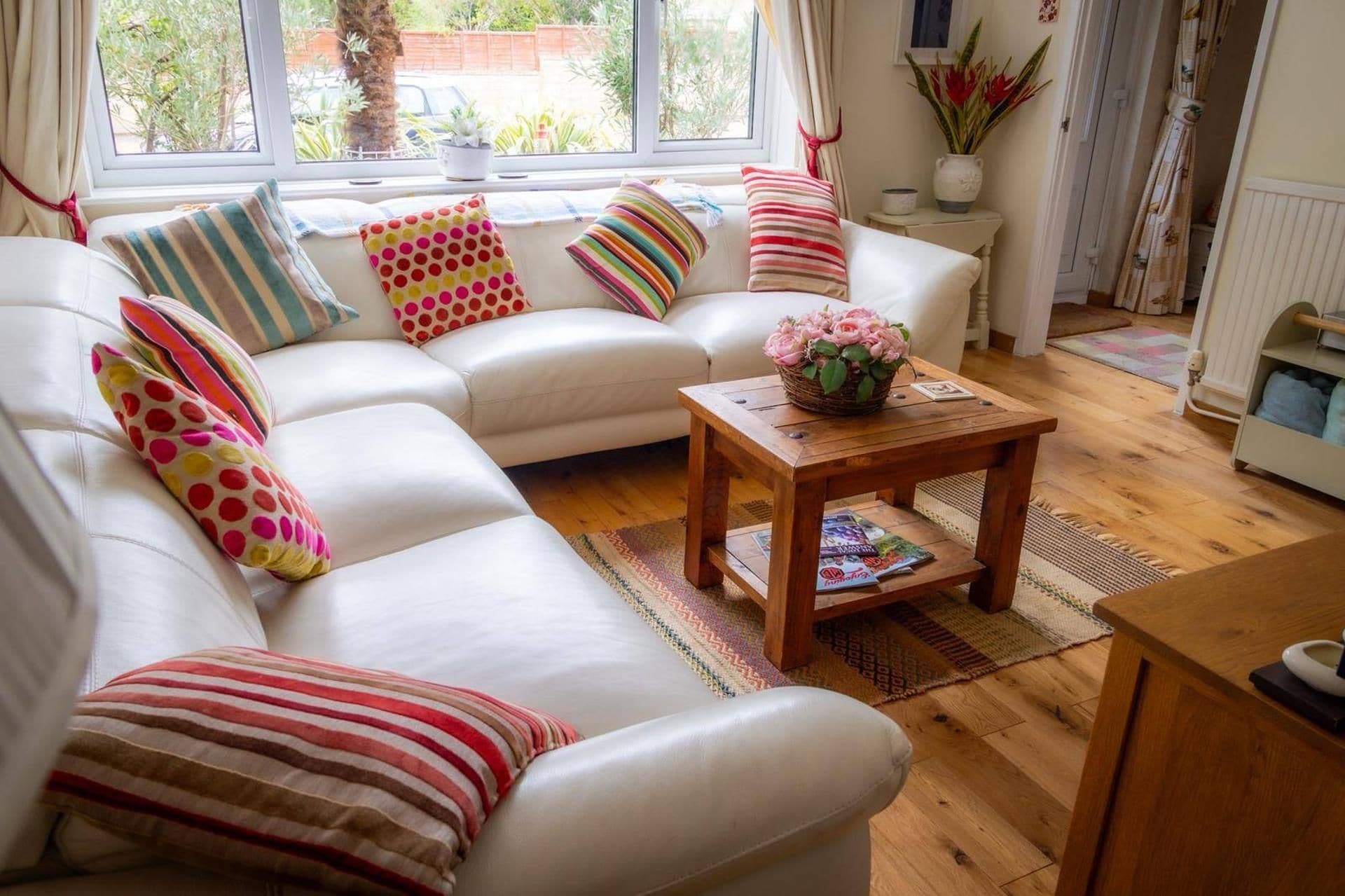 A living room with a sectional sofa, a wooden coffee table, and a window with curtains.