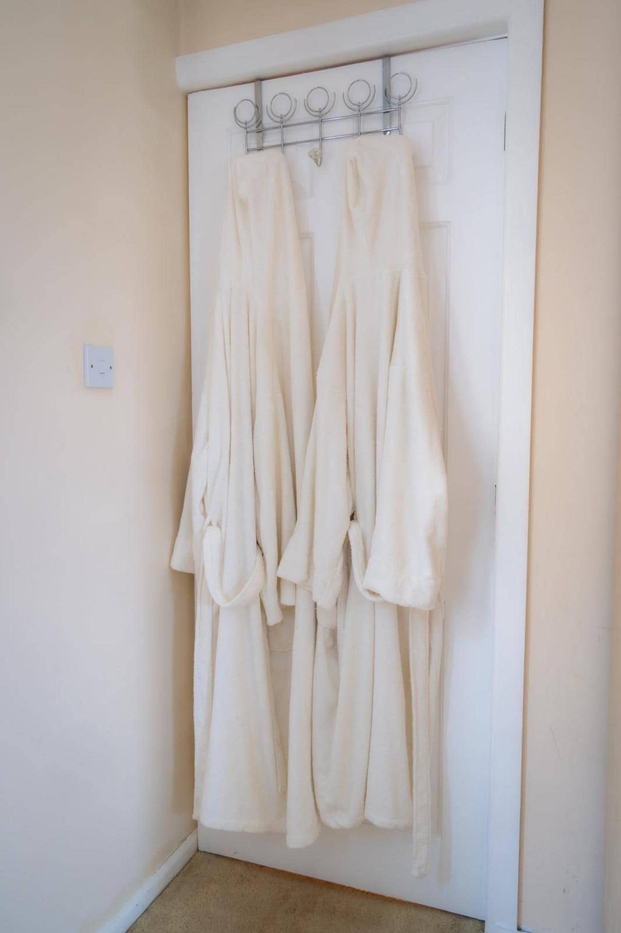 A white door with a metal towel rack holding several white towels.