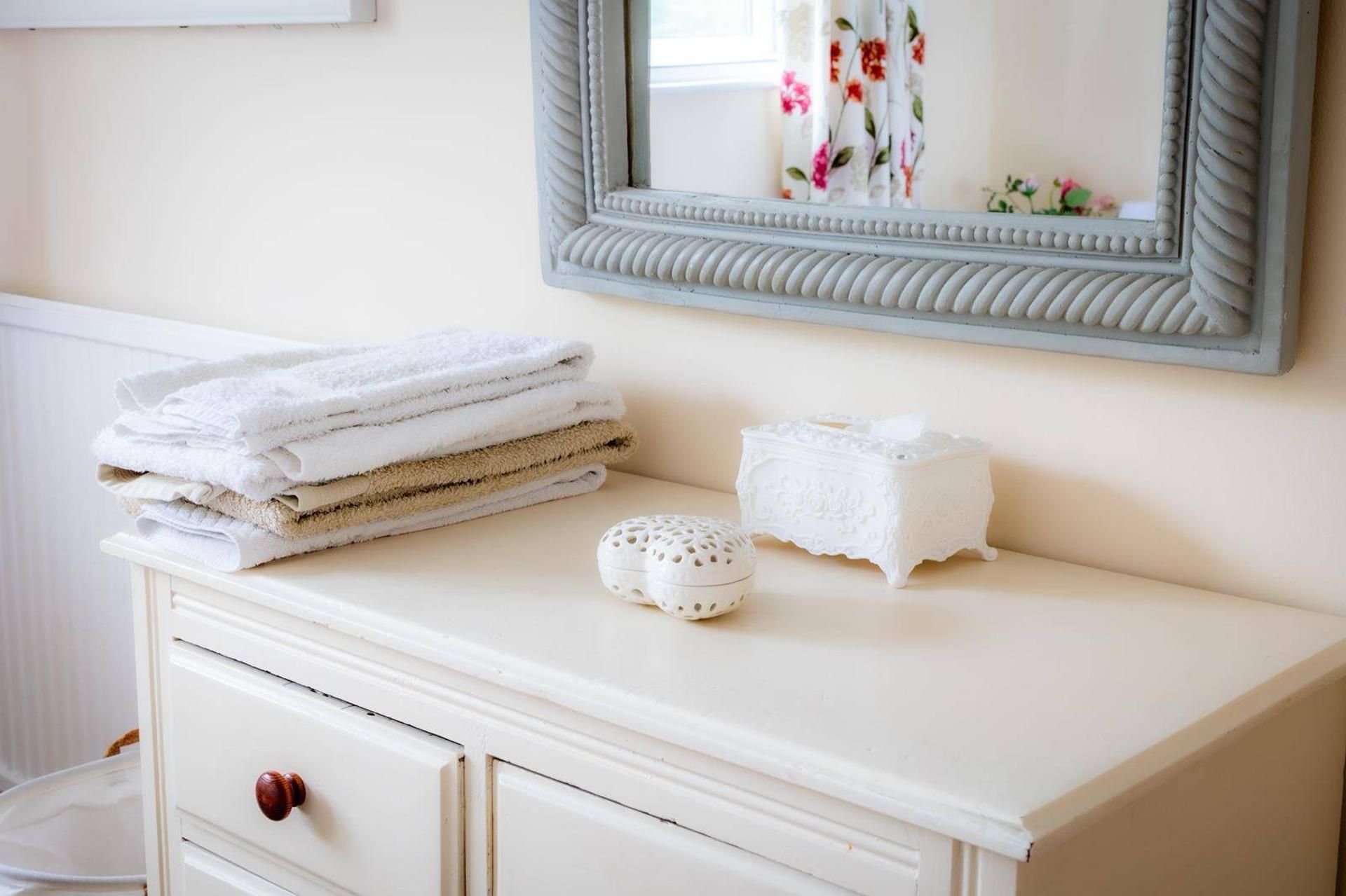 A bathroom vanity with a stack of towels, a decorative soap dish, and a mirror.
