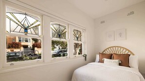 Quarto com cama, janela com vista para o exterior e obra de arte na parede.