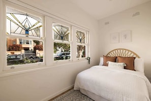 Ein Schlafzimmer mit einem Bett, einem Fenster mit Ausblick und einem an der Wand befestigten Kunstwerk.