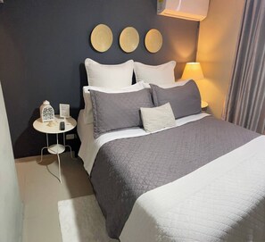 A neatly arranged bedroom with a bed, bedside tables, a lamp, and decorative wall plates. - Cozy 2nd Floorapt High Speed Internet (Santo Domingo Este)