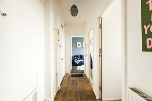 A narrow hallway with wooden flooring, white walls, and a blue room at the end. - Entire apartment in Brixton (London)