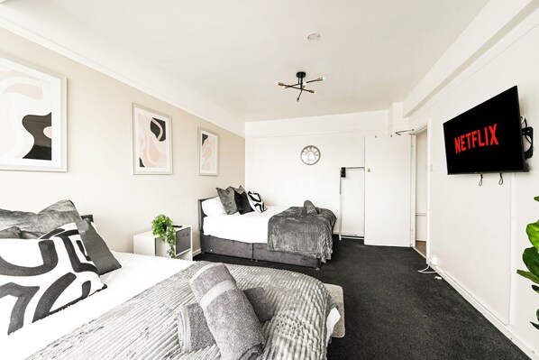 A modern hotel room with a bed, a TV, and artwork on the wall. - Entire apartment in Brixton (London)