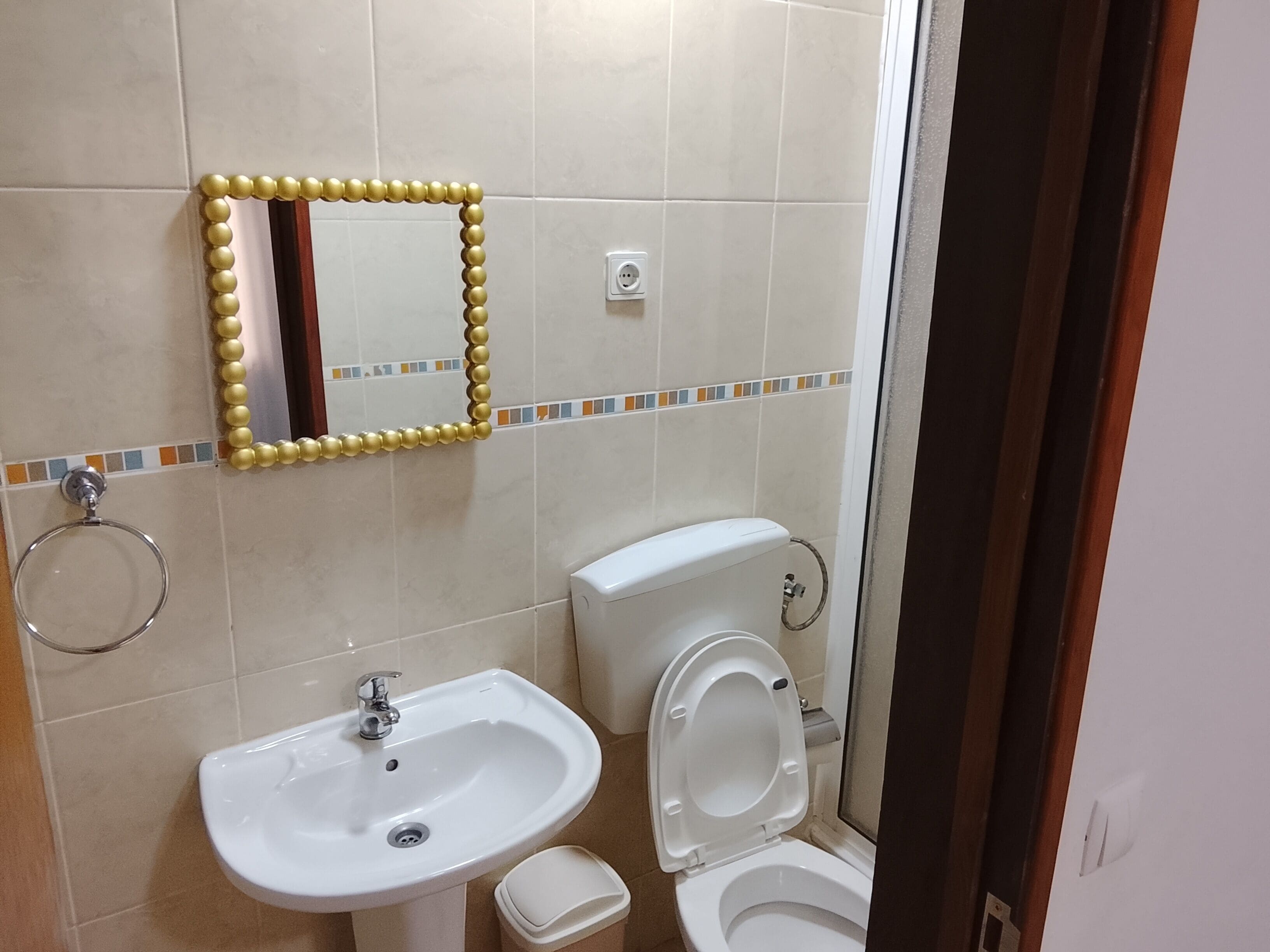 Un baño con lavamanos, inodoro y espejo.