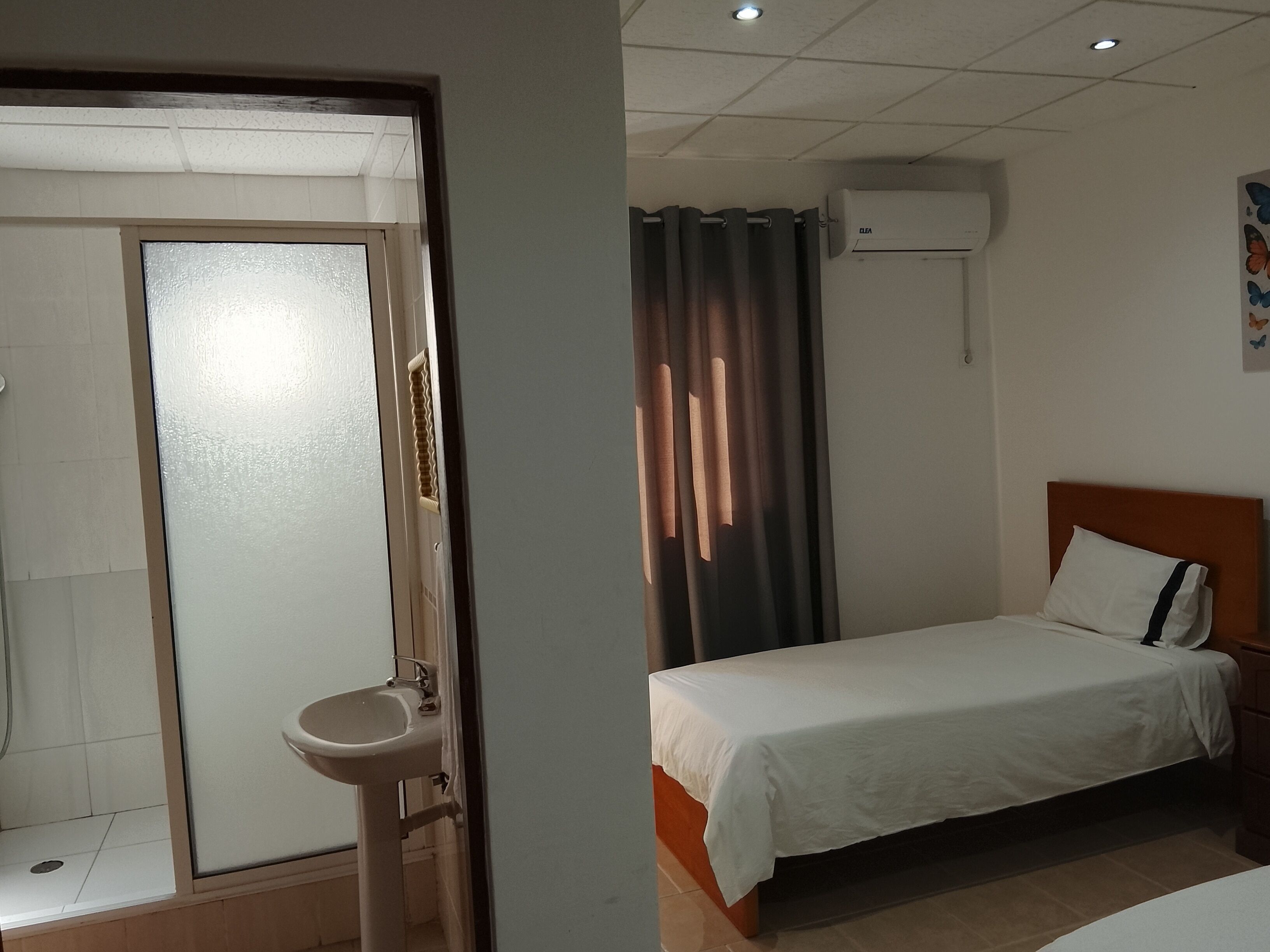 Et hotelværelse med seng, håndvask, brusebad og aircondition.