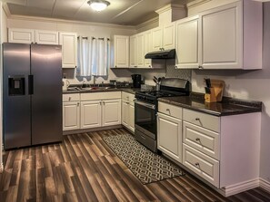 Une cuisine moderne avec des meubles blancs, des appareils en acier inoxydable et un tapis à motifs.