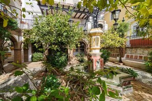 A courtyard with a fountain, stone benches, and lush greenery. - Sunny Corner Apt in Puebla Aida Golf (Mijas)