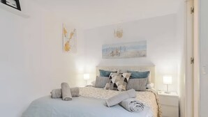 Ein Schlafzimmer mit Bett, Kissen, einem Nachttisch, einer Lampe und einem Bild an der Wand.