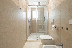 Moderni kylpyhuone, jossa on lasiseinällä varustettu suihku, wc ja pesuallas.