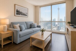 Ein modernes Wohnzimmer mit Sofa, Couchtisch, Fernseher, Lampe und einem Fenster mit Blick auf die Stadt.