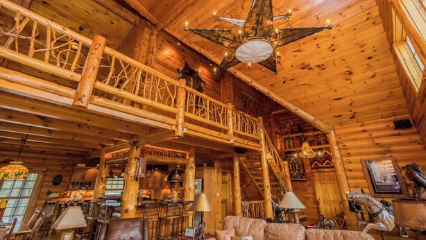 A log cabin interior with a wooden staircase, a dining area, and a large chandelier. - Unique Log Cabin, Hudson Riverfront, minutes to Saratoga (Melrose)