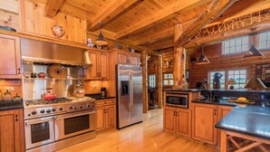 A spacious kitchen with wooden cabinets, stainless steel appliances, and a large island. - Unique Log Cabin, Hudson Riverfront, minutes to Saratoga (Melrose)