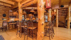 A log cabin interior with a central wooden table, bar stools, and a hanging lantern. - Unique Log Cabin, Hudson Riverfront, minutes to Saratoga (Melrose)