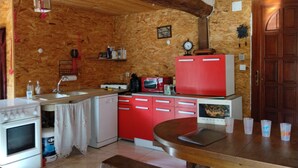 Una cucina con pareti in legno, un frigorifero rosso, una cucina a gas bianca e un tavolo da pranzo in legno.