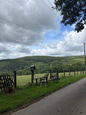 Un paysage rural avec une clôture en bois, des chaises et une nichoir.
