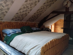 Une chambre à coucher avec un lit en bois, une couverture verte et un oreiller à motifs bleus et blancs.