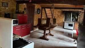 Una cucina rustica con un tavolo di legno, pensili rossi, un forno a microonde e un fornello.