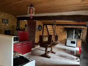 Una cocina rústica con una mesa de madera, armarios rojos, un microondas y una estufa.