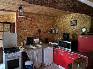 Una cocina compacta con estufa a gas, microondas, lavavajillas y armarios rojos.