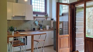 A kitchen with a wooden table, bar stools, a window, and a door leading outside. - Artist's Historic Countryside Retreat (Verona)