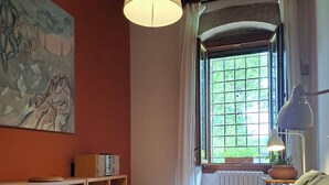 A room with a wooden bookshelf, a sofa, a hanging lamp, a window with curtains, and a painting on the wall. - Artist's Historic Countryside Retreat (Verona)