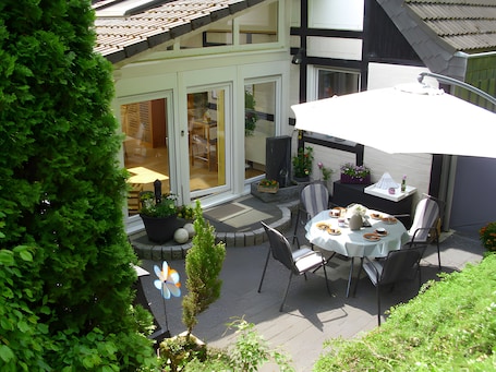 An outdoor patio area with a table and chairs, a potted plant, and a view of the building's entrance.. Apartment 'Vacation Home Haus Am Wald' with Wi-Fi