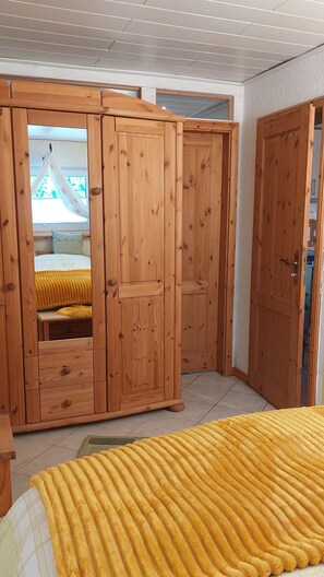 A bedroom with a bed, wooden wardrobe, and a door. - Apartment "Relax in The House By The Forest" with Wi-Fi (Drolshagen)
