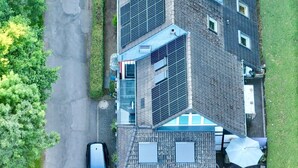 Un immeuble à plusieurs étages doté de panneaux solaires, une voiture garée devant et une pelouse bien entretenue.