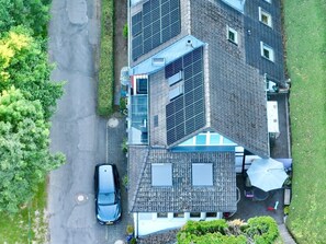 A multi-story building with solar panels, a car parked in front, and a well-maintained lawn. - Apartment "Relax in The House By The Forest" with Wi-Fi (Drolshagen)