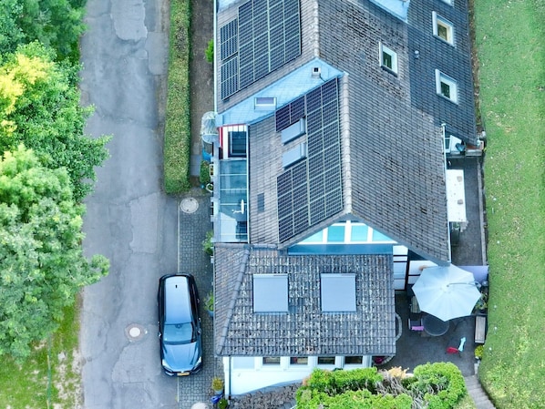 Ein mehrstöckiges Gebäude mit Solaranlage, einem geparkten Auto davor und einem gepflegten Rasen.