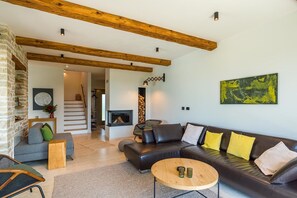 A modern living room with a fireplace, a staircase, and a large abstract painting. - Villa Regina Sea View Retreat near Višnjan (Višnjan)
