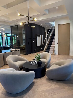 A modern interior with a round black coffee table, beige armchairs, a staircase, and a glass partition. - Luxury home in heart of Toronto. Brand new and amazing amenities. Resort like (Toronto)
