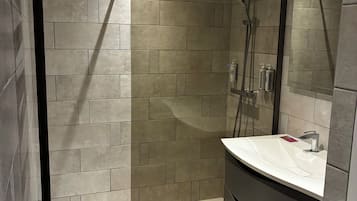 A modern bathroom with a walk-in shower, a curved vanity, and a large mirror.