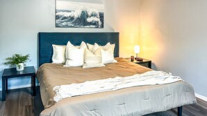 Quarto com cama, mesas de cabeceira, luminária e um quadro pendurado na parede.