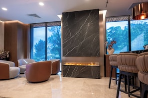 A modern interior with a fireplace, seating area, and large windows.