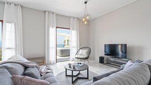 Ein modernes Wohnzimmer mit einer Couch, einem Couchtisch, einem Fernseher und Blick auf einen Balkon.