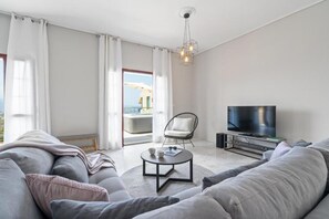 A modern living room with a sofa, a coffee table, a TV, and a balcony view. - STR Sodi The View (Chania)