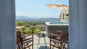 Ein Balkon mit Whirlpool, Sitzgelegenheit und Blick auf eine Stadtlandschaft.