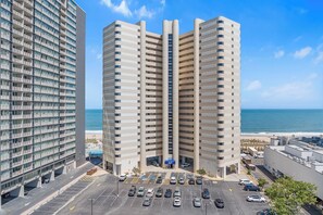 Ein Hochhaus-Hotel mit Parkplatz und Blick auf den Strand.
