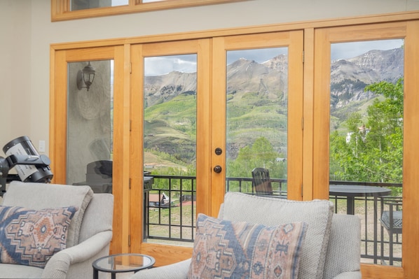A room with a sofa, a small table, and a view of a mountainous landscape through large glass doors. - Aspen Ridge 25 3 Bedroom Townhouse (Telluride)